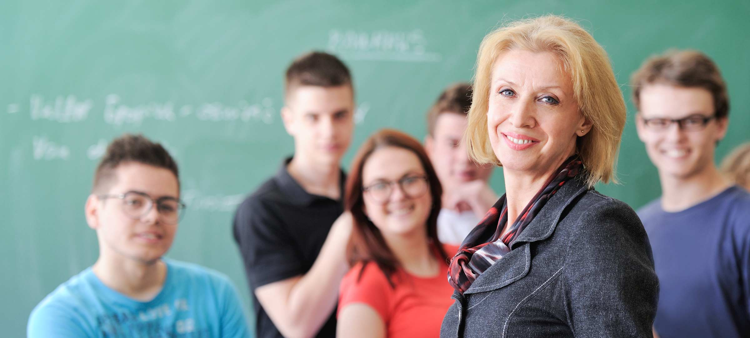 Vorschaubild: Lehrerin steht im Klassenraum vor ihrer Klasse