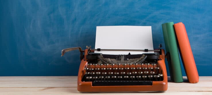Bild von einer Schreibmaschine, an der zwei Bücher lehnen