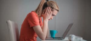 Bild von einer Frau, die verzweifelt vor dem Laptop sitzt