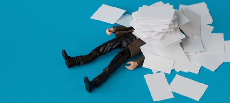 bild von einer spielfigur die unter einem papierstapel begraben ist grin |
