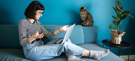 Bild von einer Frau, die mit dem Laptop auf dem Sofa sitzt