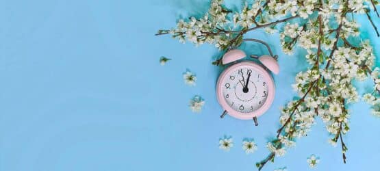 kleiner rosa Wecker vor hellblauem Hintergrund