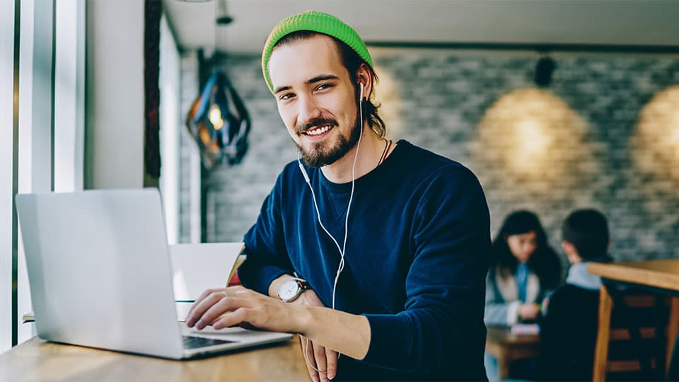 Bild eines Studenten mit grüner Mütze am Laptop