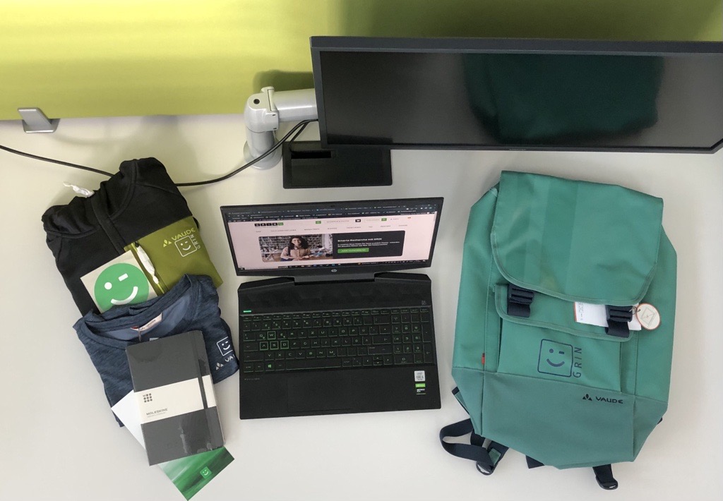 Ein Welcome Package mit einem Laptop, einem Rucksack, einem Notizbuch, Kleidung und einer Karte.